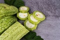 Close-up of sliced and whole bitter melons with leaves on textured surface Royalty Free Stock Photo