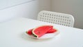 Close-up slices of fresh ripe red watermelon on a plate with a knife on the table on a white background, half of a watermelon. Royalty Free Stock Photo