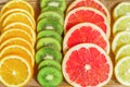 Close up of slices of oranges, lemons, kiwi, grapefruit pattern on wooden background