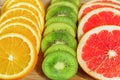 Close up of slices of oranges, lemons, kiwi, grapefruit pattern on wooden background