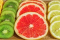 Close up of slices of oranges, lemons, kiwi, grapefruit pattern on wooden background