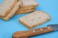 Close-up of slices of rye bread with bran / knife on a blue background. Sliced black bread Royalty Free Stock Photo