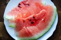 Close-up slices of watermelon on a white plate on a wooden table with copy space. Ripe red watermelon cut into slices on a wooden