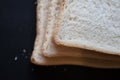 A close up of 3 slices of white bread against a black background