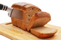 close-up of slicing loaf of rye bread with knife on cutting board on white background Royalty Free Stock Photo