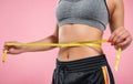 Close up of slim woman measuring her waist`s size with tape measure on pink Royalty Free Stock Photo