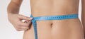 Close up slim young woman measuring her thin waist with a tape measure. Royalty Free Stock Photo