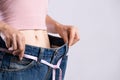 Close up slim young woman measuring her thin waist with a tape measure. Healthcare and woman diet lifestyle concept to reduce Royalty Free Stock Photo