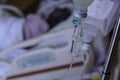 close up of a slow intravenous drip with a blurred lit neon in the background in a hospital room Royalty Free Stock Photo