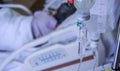 close up of a slow intravenous drip with a blurred lit neon in the background in a hospital room Royalty Free Stock Photo
