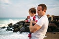 Close up of small baby girl in sweatshirt in father`s hands on the sea coast Royalty Free Stock Photo