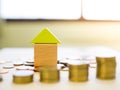 Close up small blocks house with stack of coins