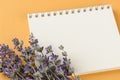 Close-up of small bouquet of fragrant blooming lavender on a blank paper notepad over a textural yellow background. Summer and