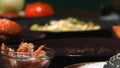 Close-up of small bowl with shrimps and male chef in blue apron taking a few shrimps and adding them in a hamburger Royalty Free Stock Photo