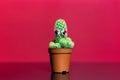 Close-up of small cactus in pot with artificial red eyes on red background.