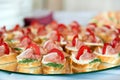 Close up of small canapes arranged on a mirror plate over light background Royalty Free Stock Photo