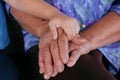 Close-up of small child hand holdiing on elderly person`s hand grandmother with Alzheimer and Parkinson disease. Concepts of