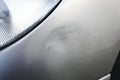 Close up of small dent and scratches on silver gray car. Car with damage from crash accident, parking lot or traffic. Royalty Free Stock Photo