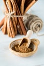 A small dish of cinnamon powder with a tied bundle of cinnamon sticks in behind.