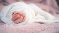 Close up small feet of baby infant sleeping on soft bed covered with white cloth. Royalty Free Stock Photo