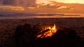 CLOSE UP: Small fire burns inside a fireplace on the sandy beach at sunset. Royalty Free Stock Photo