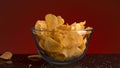 Close up of a small glass bowl and many potato chips falling into it and on the dark table. Stock footage. Spicy Royalty Free Stock Photo