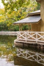 Close-up of small house, with reflection in the water, on the edge of a pond with autumnal vegetation, vertically Royalty Free Stock Photo