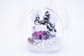 Close up of the small house in a snowy forest among the firs inside the transparent Christmas ball, White background, copy space. Royalty Free Stock Photo