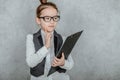 Close-up of a small lady boss is on a gray background. During this, holds the black folder and the yellow pencil Royalty Free Stock Photo