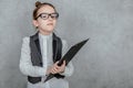 Close-up of a small lady boss is on a gray background. During this, holds a black folder and a yellow pencil, looking Royalty Free Stock Photo