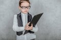 Close-up of a small lady boss is on a gray background. During this, holds a black folder and a yellow pencil while Royalty Free Stock Photo