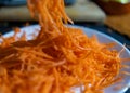 Pile of grated carrot on white plate with blurry background