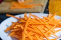 Pile of thin carrot slices on white plate with blurry background