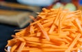 Pile of thin carrot slices on white plate with blurry background