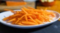Pile of thin carrot slices on white plate with blurry background