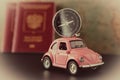 Close-up. Small pink car with a compass on the roof and passports on a background of vintage maps, travel concept Royalty Free Stock Photo