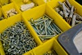 Close-up of small plastic yellow boxes with different screws and fasteners. Selective focus Royalty Free Stock Photo