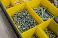 Close-up of small plastic yellow boxes with different screws and fasteners. Selective focus Royalty Free Stock Photo