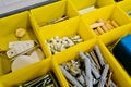 Close-up of small plastic yellow boxes with different screws and fasteners. Selective focus Royalty Free Stock Photo