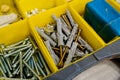 Close-up of small plastic yellow boxes with different screws and fasteners. Selective focus Royalty Free Stock Photo