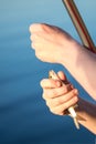 Close-up small redeye fish in man hand against blue pond water. Fisherman taking out hook. Newcomer fishing background. Copysp