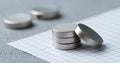 Close-up of small round silver magnets stacked on graph paper with blurred magnets in the background on textured surface Royalty Free Stock Photo