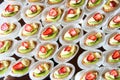 Close up of small sweet canapes arranged on a mirror plate over light background Royalty Free Stock Photo