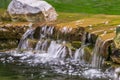 Close-up of small waterfall running over rocks with autumn leaves