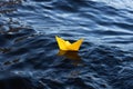 Close-up of a small yellow origami paper boat in blue water. The concept of travel, discoveries of freedom Royalty Free Stock Photo