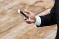 Close-up smart Business man wearing modern black suit and white shirt and texting on mobile smart phone. Royalty Free Stock Photo