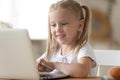Smart little girl using laptop learning online at home Royalty Free Stock Photo