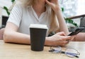 Close up of a smartphone being used by cheerful young caucasian blond business woman in a white shirt sitting at the table. Nearby Royalty Free Stock Photo