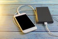 Close up smartphone charging with power bank on blue background with copy space. Smartphone charging with power bank by white USB Royalty Free Stock Photo
