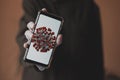 Close-up of a smartphone in the hands in gloves with the image of a coronavirus. Illustration of COVID-19.